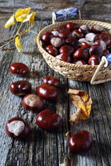 Chestnuts in  wicker basket and autumn leaves