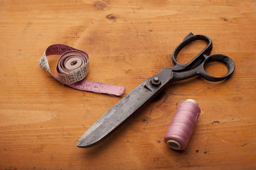 dressmaker shears craft concept with spool and measuring tape on