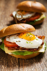 Sandwich with a fried egg, bacon, cheese and vegetables.