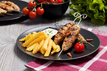 Barbecued kofta - kebeb with fries and vegetables on a plate.