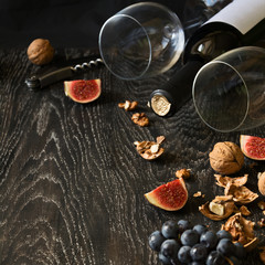 Red wine, two wineglass with walnuts, grapes and figs on dark wooden background