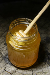 jar of honey and stick to honey on a wooden background