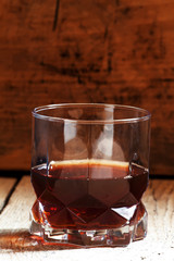 Whisky in a glass on old wooden dark background, selective focus