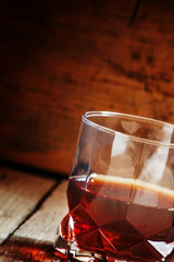 Whisky in a glass on old wooden dark background, selective focus