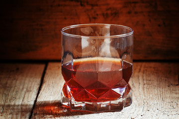 Whisky in a glass on old wooden dark background, selective focus