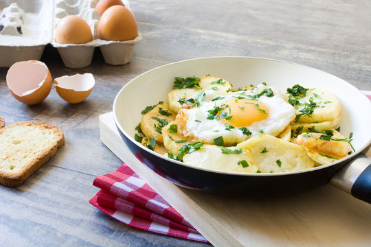 Potatoes, fried eggs and parsley in a frying pan
