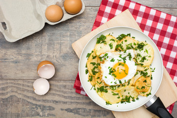 Potatoes, fried eggs and parsley in a frying pan