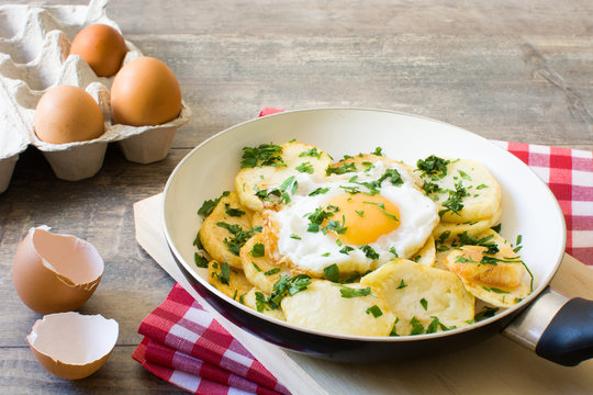 Potatoes, fried eggs and parsley in a frying pan
