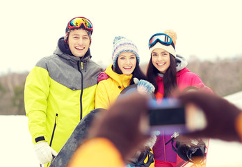 happy friends with snowboards and smartphone