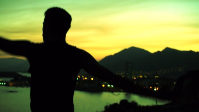 hombre bailando como un tonto en paisaje costero a contraluz