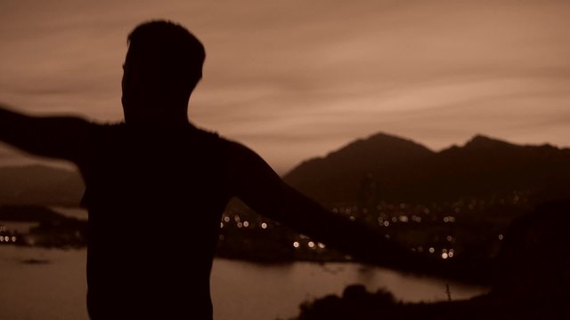 hombre bailando como un tonto en paisaje costero a contraluz