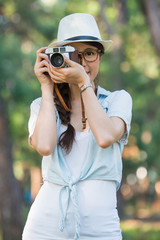 Beautiful young girl smiling with retro camera photographing, ou