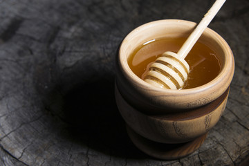 jar of honey and stick to honey on a wooden background