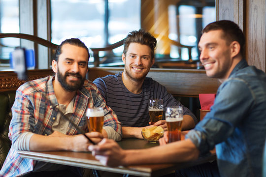 friends taking selfie and drinking beer at bar