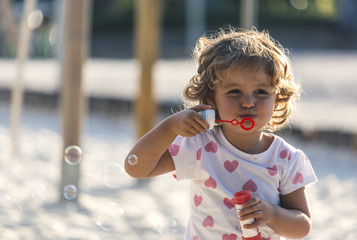Little girl making soap bubbles at playground