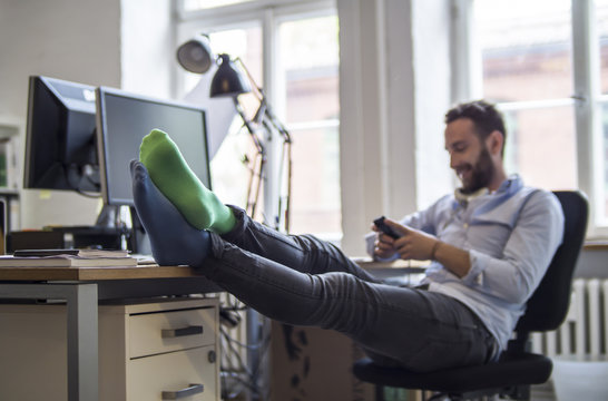 Young man in office with feet on desk wearing different socks