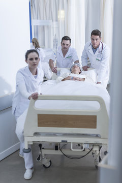 Hospital staff pushing bed with patient on floor