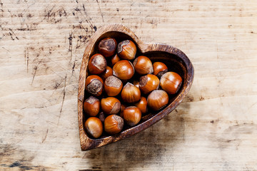 Fresh hazelnuts in a wooden bowl in the shape of a heart, top vi