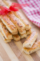 Bread Salty Grissini Sticks with sesame and flax seeds prepared for New Year's Day with red ribbon and red Christmas decorations