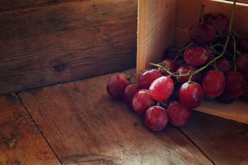 low key image of red grapes over wooden textured table
