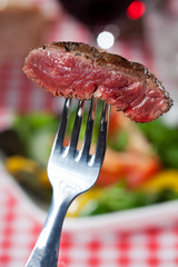Steakscheibe auf einer Gabel über Salat