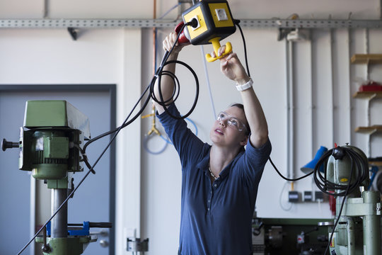 Young woman with safety goggles installing a three-phase plug