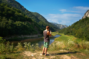 Fototapeta premium Young man taking picture of beatiful landscape