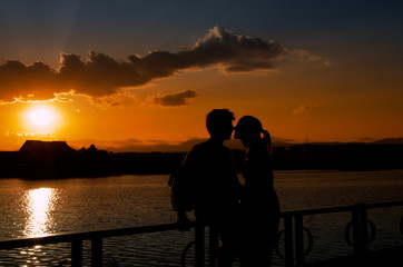 Young couple silhouettes kissing at sunset