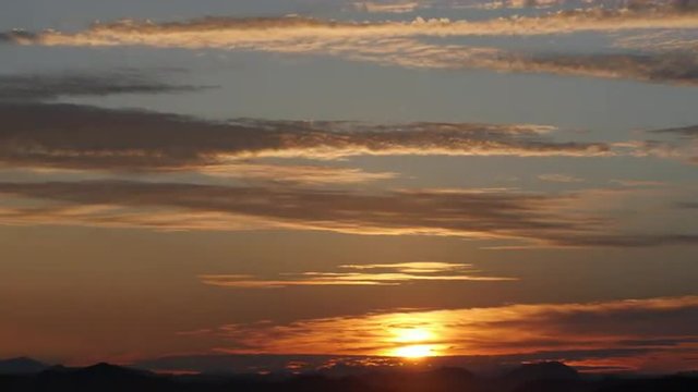 Layers of cirrus clouds illuminated by the rising sun. 4K UHD time-lapse.