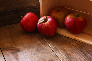 low key image of red apples over wodden textured table
