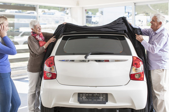 Father and mother unveiling new car as gift for the daughter