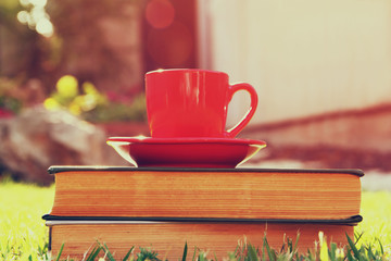 coffee cup mug and book over wooden table outdoors, at afternoon time. selective focus

