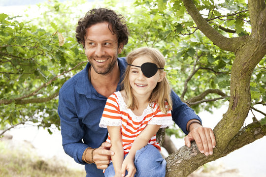 Father with daughter dressed up as pirate sitting on a tree