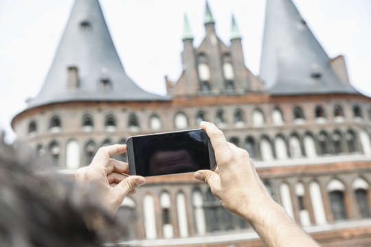 Germany, Luebeck, man taking picture in front of the Holsten Gate