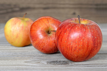 Three red apples on wooden background