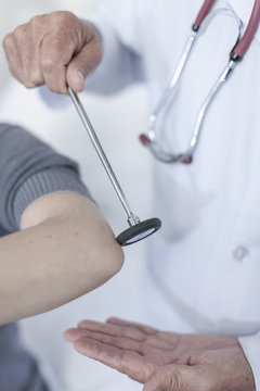 Doctor tapping patient with reflex hammer