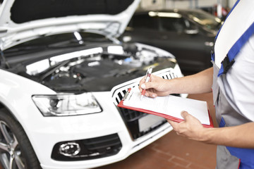 Car mechanic holding clipboard in a garage