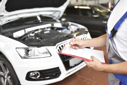 Car mechanic holding clipboard in a garage