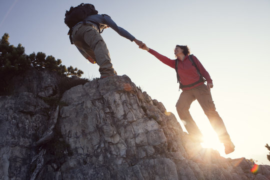 Austria, Tyrol, Unterberghorn, man helping woman on hiking trip