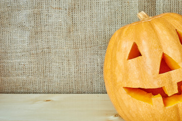 Halloween orange pumpkin on a burlap background in a rustic styl