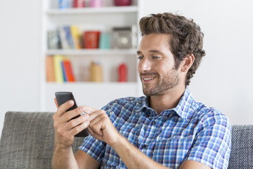 In modern apartment a mid adult man using mobile phone