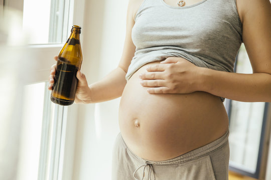 Pregnant woman holding a bottle of beer