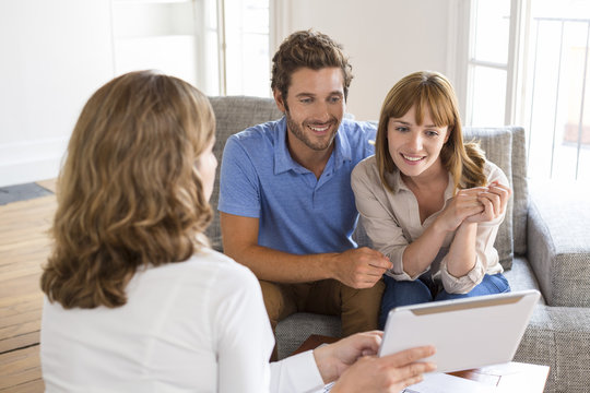 Real-estate agent presenting to a couple a project property on tablet PC