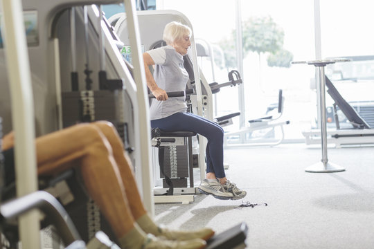 Senior woman in gym exercising at dip machine