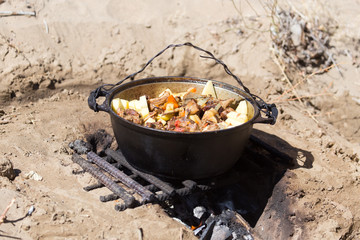 meat with potatoes in a cauldron on fire