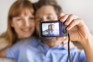 Cheerful couple taking a selfie with a camera. White home 