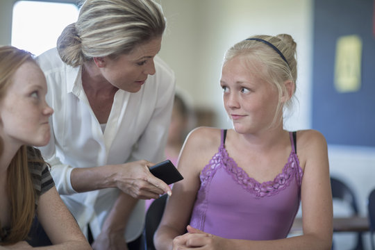 Teacher with cell phone in classroom scolding schoolgirls - Powered by Adobe