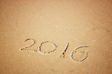 new year 2016 written in sandy beach. image is retro filtered
