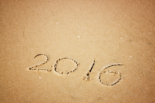 new year 2016 written in sandy beach. image is retro filtered
