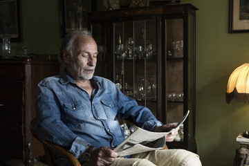 Senior man reading newspaper at home